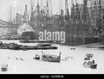 Die Kräne von Londons Uferpromenade über der Tower Bridge bilden eine Kulisse für das Wikinger-Langschiff „Hugin“ aus dem Jahr 1949, während seine Besatzung von Wikingerkriegern vom Tower Pier nach Richmond in Surrey ruht. Stockfoto