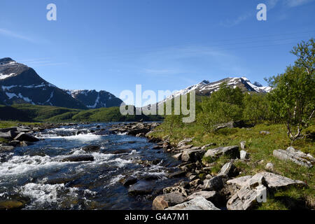 Kleinen Bach mit den schneebedeckten Bergen im Hintergrund, Bild aus dem Norden von Norwegen. Stockfoto