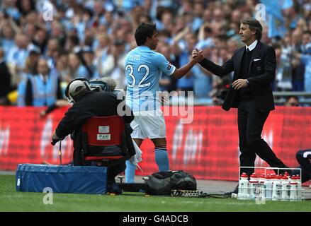 Carlos Tevez von Manchester City schüttelt sich die Hände mit Manager Roberto Mancini Nachdem er ersetzt wird Stockfoto