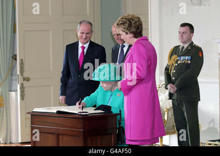 Die britische Königin Elizabeth II. Unterschreibt das Besucherbuch, das der Herzog von Edinburgh, die Präsidentin Mary McAleese und Dr. Martin McAleese in Aras an Uachtarain im Phoenix Park, Dublin, beobachtet haben. Stockfoto