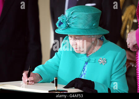 Die britische Königin Elizabeth II. Unterschreibt das Besucherbuch in Aras an Uachtarain (dem offiziellen Wohnsitz des irischen Präsidenten) im Phoenix Park, Dublin, Irland. Stockfoto