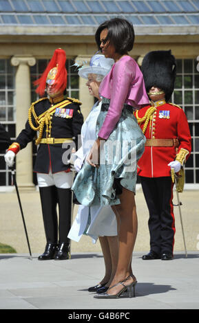 Der Rock der US First Lady Michelle Obama (rechts) ist im Wind gefangen, als sie mit Königin Elizabeth II. Im Garten des Buckingham Palace in London steht, am ersten Tag des dreitägigen Staatsbesuchs von Präsident Obama in Großbritannien. Stockfoto