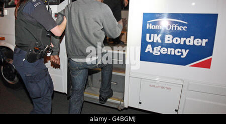 Ein Mann wird von einem Beamten der britischen Grenzbehörde während einer Suche nach illegalen Arbeitnehmern bei Honeytop Foods in Dunstable, Bedfordshire, verhaftet. Stockfoto