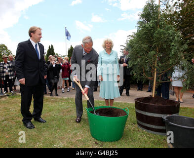 Der Prinz von Wales und die Herzogin von Cornwall Pflanzen einen Baum, begleitet von General Manager Christopher White (links) bei einem Besuch im Denbies Wine Estate in Dorking, Surrey, während sie eine Reihe von Engagements in der ganzen Grafschaft Unternehmen. Stockfoto