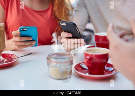 -MODELL VERÖFFENTLICHT. Junge Menschen im Café mit Smartphones. Stockfoto