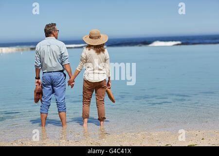 -MODELL VERÖFFENTLICHT. Älteres Paar Hand in Hand, Paddeln im Meer. Stockfoto