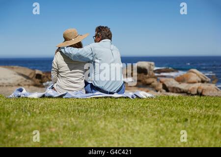 -MODELL VERÖFFENTLICHT. Älteres Paar auf der Picknickdecke, Mann mit Arm um die Schultern der Frau. Stockfoto
