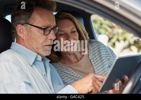 -MODELL VERÖFFENTLICHT. Älteres Paar im Auto mit einem digital-Tablette. Stockfoto