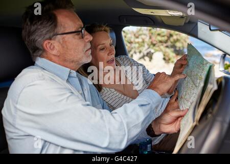 -MODELL VERÖFFENTLICHT. Älteres Paar im Auto Lesen einer Karte. Stockfoto