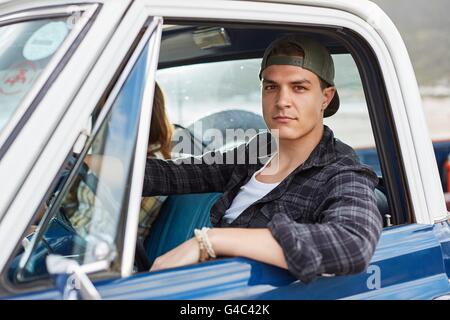 -MODELL VERÖFFENTLICHT. Junger Mann, Blick in die Kamera durch offenen Autofenster. Stockfoto