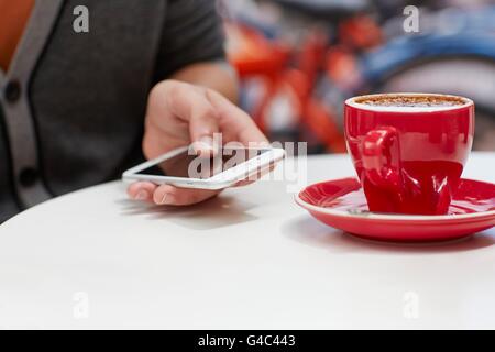 -MODELL VERÖFFENTLICHT. Person mit Smartphone mit Kaffee, Nahaufnahme. Stockfoto