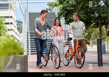 -MODELL VERÖFFENTLICHT. Junge Paare, die mit Fahrrädern. Stockfoto