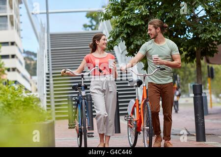 -MODELL VERÖFFENTLICHT. Junge Paare, die mit Fahrrädern. Stockfoto