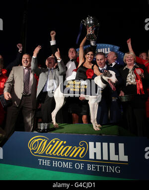 Taylors Sky und seine Besitzer Rebecca (Mitte, mit Trophäe) und Steve Taylor (Cenre links) feiern nach dem Gewinn des Greyhound-Derby-Finales Williamhill.com im Wimbledon Stadium im Süden Londons. Stockfoto