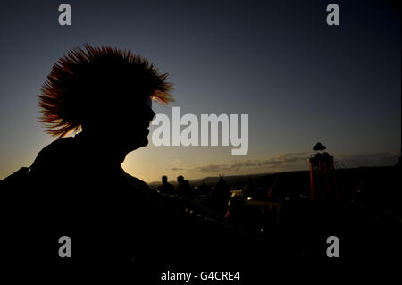 Nachtschwärmer genießen den Sonnenuntergang, während sie sich in der Nähe des Parks beim Glastonbury Musikfestival auf der Worthy Farm, Pilton, entspannen. Stockfoto