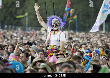 Ein Nachtschwärmer, gekleidet wie ein gruseliger Clown, erhebt sich vor der Pyramid Stage beim Glastonbury Musikfestival auf der Worthy Farm, Pilton. Stockfoto