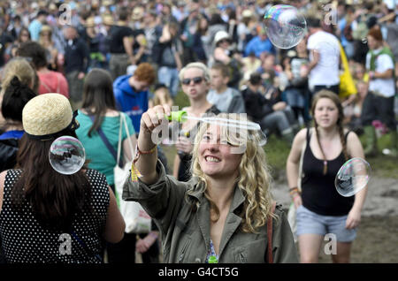 Ein Nachtschwärmer bläht mit einem Blasenstab in den Massen vor der Pyramid Stage beim Glastonbury Musikfestival in Worthy Farm, Pilton. Stockfoto