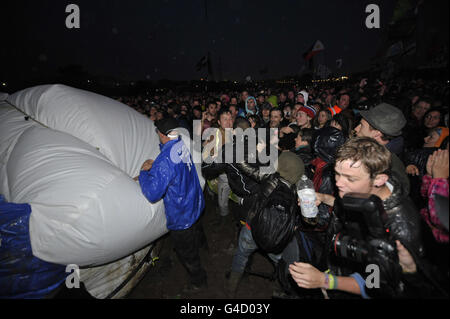 Sicherheitspersonal und Mitglieder der direkten Aktionsgruppe Art Uncut, tossle über einen 20 Fuß großen Ballon mit der Botschaft "U Pay Your Tax 2", während die Rockband U2 auf der Pyramid Stage beim Glastonbury Musikfestival in Worthy Farm, Pilton auftreten. Stockfoto