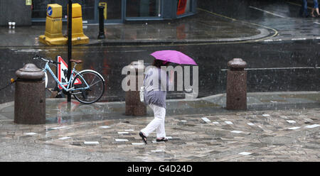 Eine Frau geht durch den Regen vor der St Paul's Cathedral in London, während Teile des Landes sich auf Blitzüberflutungen einlassen. Stockfoto