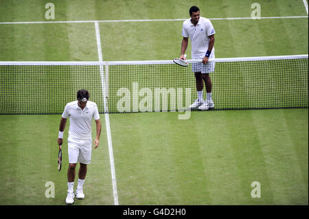 Tennis - Wimbledon Championships 2011 - Tag neun - All England Lawn Tennis und Croquet Club. Der Schweizer Roger Federer und der französische Jo Wilfried Tsonga (rechts) reagieren auf einen Punkt Stockfoto