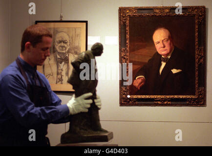 Ein Mann aus Sotheby's bewegt vor dem Verkauf politischer Erinnerungsstücke eine Statue von Oscar Nemon von Sir Winston Churchill vor einem Porträt von John Berrie. Stockfoto