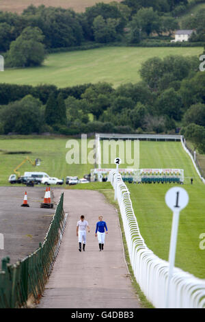 Zwei Jockeys laufen neben einem leeren Platz auf der Rennbahn Chepstow Stockfoto
