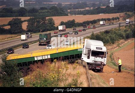 Ein Polizist inspiziert einen Sattelschlepper, der einen Damm auf der Autobahn M20 nördlich von Ashford in Kent aufbohrt, nachdem er in einen auf der harten Schulter geparkten Lieferwagen abgestürzt ist. Der Fahrer des Transporters erlitt tödliche Verletzungen. Foto von Ben Curtis/PA. Stockfoto