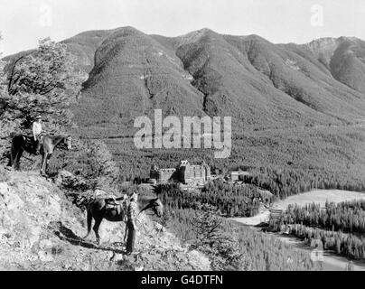 Zwei Reiter halten inne, um die herrliche Aussicht zu genießen Kanadas Rocky Mountains als Banff Springs Hotel kann man sehen In der Ferne gelegen Stockfoto