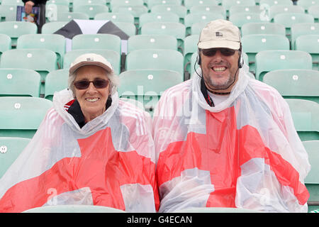 Fans sitzen auf den Tribünen, die in einem England Poncho bedeckt sind, und schützen sich vor dem Regen während des ersten NatWest One Day International im Kia Oval, London. Stockfoto