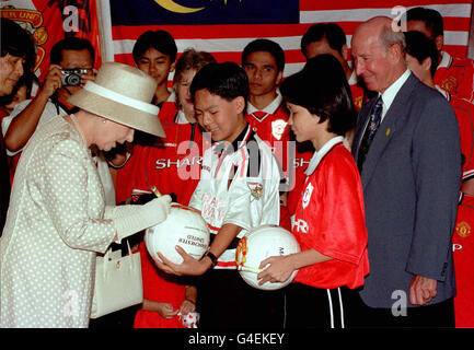 Die Königin unterzeichnet einen Manchester United Fußball von Nicolas How, 13 gehalten, (der Duke of Edinburgh unterzeichnet der Fußballs im Besitz Elianoor Munning, 13) für malaysische Manchester United Football Club Unterstützer in der Suria KLCC Shopping Centre in Kuala Lumpur heute (Dienstag), am vorletzten Tag Ihres Besuch in Malaysia. Ehemalige Manchester United und England Fußball-Star, Sir Bobby Charlton, rechts, war ebenfalls anwesend, um sie zu begrüßen. Fotografieren von Fiona Hanson/PA Stockfoto