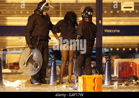 Die Polizei verhafte eine Frau vor einem Currys-Geschäft, dessen Fenster in Brixton, im Süden Londons, gebrochen worden waren, als eine zweite Nacht der Unruhen die Hauptstadt traf. Stockfoto
