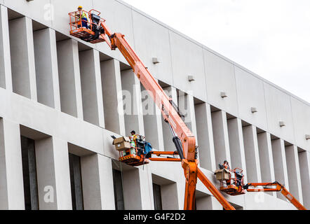 Arbeitnehmer auf Hubarbeitsbühnen, arbeitet an einer Hausfassade, Stockfoto