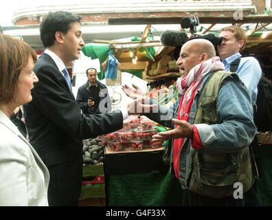 Der Labour-Vorsitzende Ed Miliband, MP, trifft Pander Kelly, einen Marktstandshändler, während eines Besuchs, um Unternehmen und Menschen zu besuchen, die von der jüngsten Störung betroffen sind, in Brixton, im Süden Londons. Stockfoto