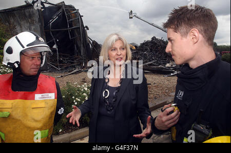 Die Innenministerin Theresa May bei den ausgebrannten Überresten des Sony Distribution Centers in Enfield North London. Stockfoto