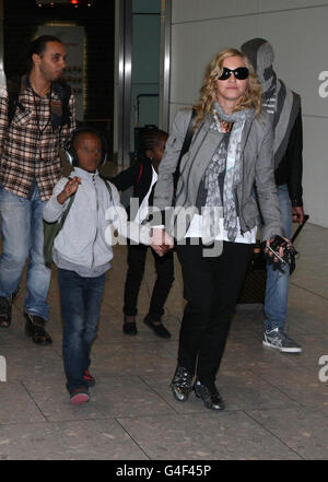 DIE REDAKTION BEMERKT, DASS DIE GESICHTER DER KINDER VOM PA-BILDTISCH VERPIXELT WURDEN. Madonna kommt von New York aus am Flughafen Heathrow in London an, mit ihrem Freund Brahim Zaibat (rechts) und den Kindern David Banda (zweite links) und Mercy James (Mitte). Stockfoto