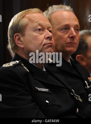 Der amtierende Metropolitan Police Commissioner Tim Godwin (links) und Sir Hugh Orde, Präsident der Association of Chief Police Officers, hören der Innenministerin Theresa May eine Rede zur Polizeireform im Zentrum von London zu. Stockfoto