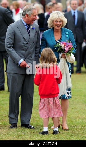 Der Prinz von Wales und die Herzogin von Cornwall sprechen mit einem Schulmädchen bei einem Besuch der Sandringham Flower Show in Sandringham, Norfolk. Stockfoto