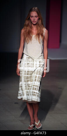 Ein Model trägt ein steinfarbenes ärmelloses T-Shirt mit einem mittellangen Rock aus Stein und Weiß aus der Paul Smith Women Summer Collection während der London Fashion Week. Stockfoto