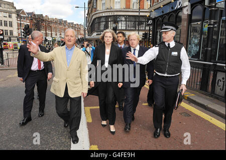 Der Londoner Bürgermeister Boris Johnson (zweiter rechts) und Innenministerin Theresa May (zweiter links) während einer Tour durch die Verwüstungen in Clapham, im Süden Londons, nach einer Nacht der Unruhen in London gestern Abend. Stockfoto