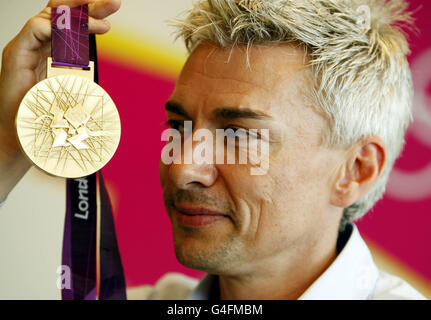 Der ehemalige britische Dreifachspringer Jonathan Edwards blickt auf die olympische Goldmedaille 2012 während einer Fotozelle im Londoner Organisationskomitee der Olympischen Spiele 2012 in Canary Wharf, London. Stockfoto