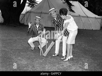 Der britische Filmstar Joan Collins zeigt Bob Hope, wie man einen Cricket-Schläger hält, während „Wicket-Keeper“ Bing Crosby auf den ungeordneten Mittelstumpf zeigt. Stockfoto