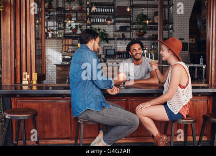 Porträt von drei jungen Freunde lächelnd und sitzen in einem Café mit Getränken zusammen. Junge Männer und Frauen treffen sich in einem Kaffee sh
