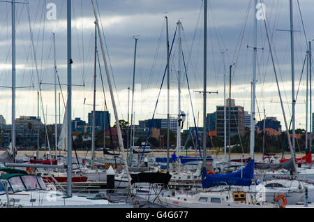 Ein Mann, der an einem bewölkten, bewölkten Tag einen Mast einer Yacht in einem Bootshafen in St. Kilda in Melbourne, Australien, besteigen kann Stockfoto