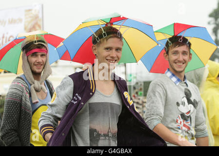 Festivalbesucher mit Regenschirmhüten kommen im Regen zum Reading Festival in der Richfield Avenue in Reading an. Stockfoto