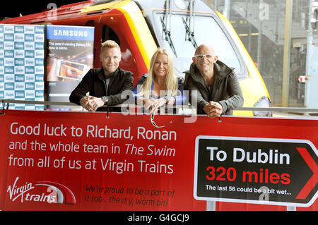 (Von links) Ronan Keating, Pamela Stephenson und Jason Bradbury posieren vor einem Virgin-Zug am Bahnhof Euston in London, bevor sie nach Holyhead in Wales einschiffen und an dem Schwimmen teilnehmen, einem Spendenschwimmen über die Irische See zugunsten von Cancer Research UK. Stockfoto