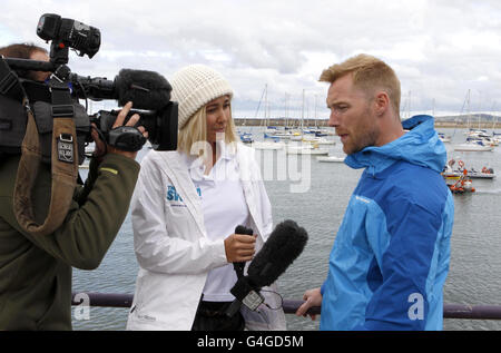 Ronan Keating und Jenny Frost im Holhead-Segelclub vor dem Schwimmen, einem Fundraising-Bad über die Irische See zugunsten von Cancer Research UK. Stockfoto