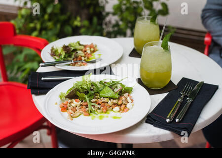 Zwei Platten aus frischer Salat mit Rucola, Mozzarella, Gemüse, Tomaten, Hähnchen Minze Limonade in einem kleinen Restaurant im Freien serviert das Mittagessen Stockfoto