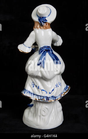 Porzellanfigur in Form eines Mädchens in mittelalterlicher Tracht auf schwarzem Hintergrund isoliert Stockfoto