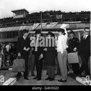 John Lennon, in einem Souvenir-Hut, schlägt eine spanische Pose für die Hunderte von Fans, die die Beatles - Paul McCartney, George Harrison & Ringo Starr auf dem Londoner Flughafen bei ihrer Rückkehr aus Spanien - schreiend begrüßen. 4/7/65 117349-1 ghgal Stockfoto