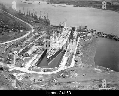 Die 85,000 Tonnen schwere 'Queen Elizabeth' nimmt fast den gesamten Bereich des riesigen King George V Docks in Southampton ein. Das riesige Schiff wird von seiner Rolle als Truppenschiff im Krieg zu seiner Rolle als Luxuskreuzfahrtschiff in der Friedenszeit umgerüstet. Stockfoto